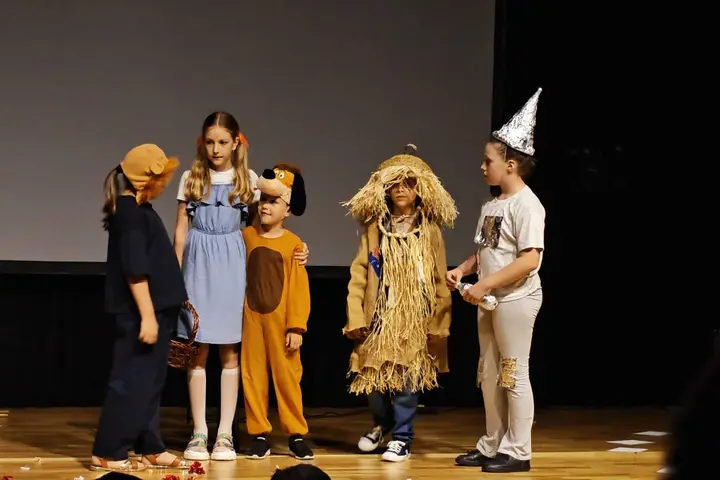 Elevi în costume de sperietoare, leu și Dorothy, într-o scenă de grup